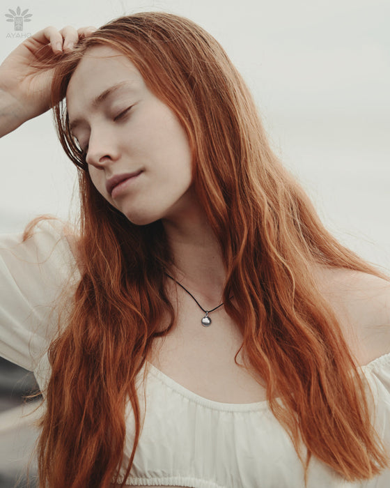 Woman with long red hair wearing a white top against a neutral background