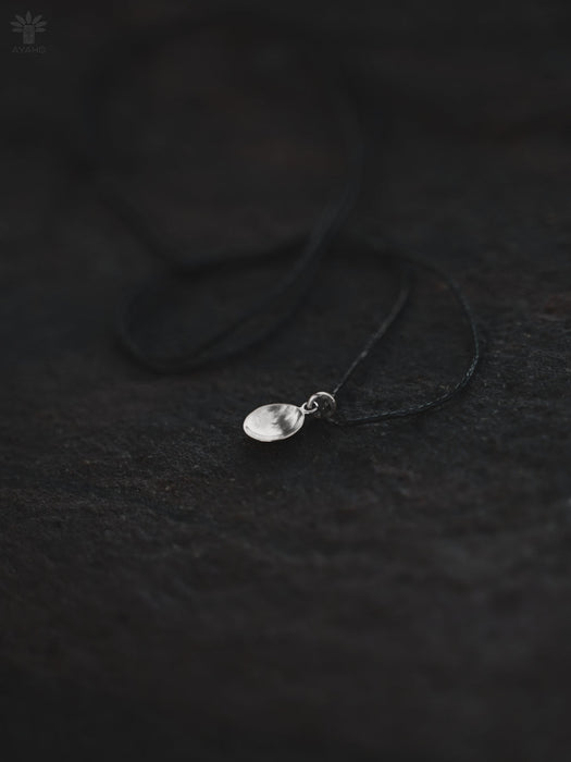 Silver necklace with a pendant on a dark textured surface