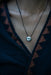 Necklace with a pendant on a person wearing a dark top.