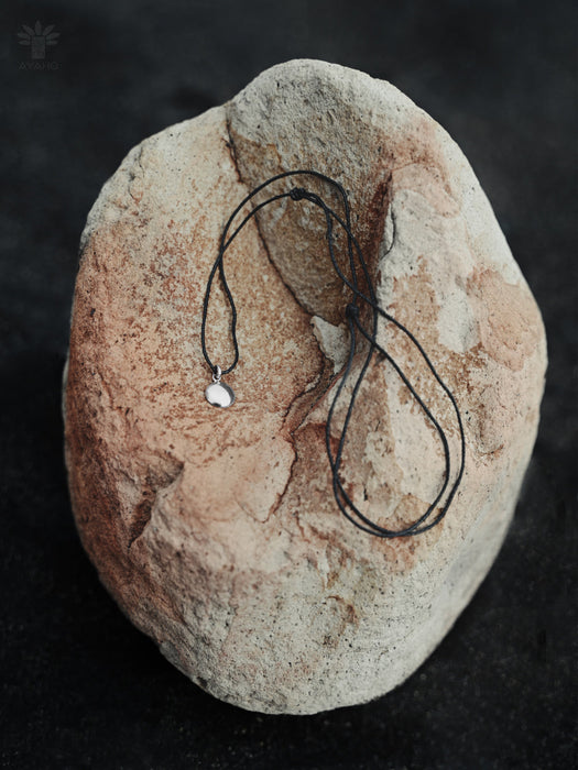 Necklace with a pendant on a textured stone surface