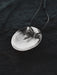 Silver pendant necklace on a dark textured background