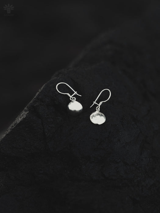 Silver earrings on a textured black surface