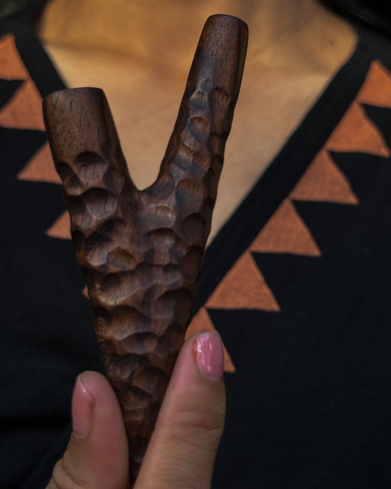 Wooden y-shaped tool held by a hand against a patterned background
