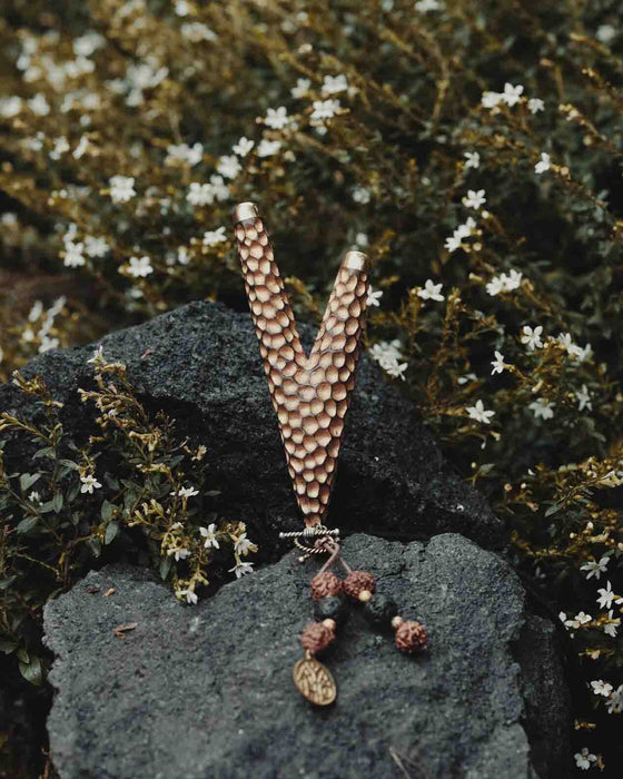 Golden Kuripe pipe, a ceremonial hape snuff applicator and shamanic tool, displayed as a necklace on weathered wood. Unique handmade smoking accessory for herbal medicine
