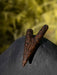 Wooden fish hook on a dark stone surface with a blurred green background