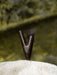 Wooden treble clef on a textured surface with a blurred natural background