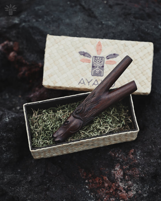 Wooden smoking tool on a bed of green moss with 'AYA' branding in the background