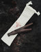 Wooden tool on a white drawstring bag with 'AYAH' branding on a dark textured background