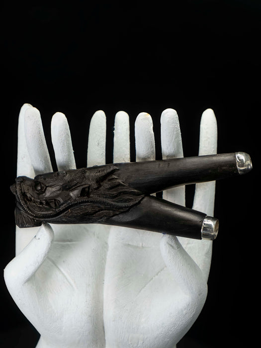 Decorative black object with intricate design on a white mannequin hand against a black background
