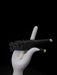 White hand holding a black gun against a black background
