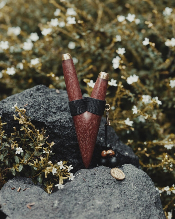 A serene woman holds a high-quality wooden kuripe blowpipe, used as a hape snuff applicator. The kuripe, doubling as a necklace with detailed charms, represents both a shamanic tool and a unique gift.