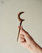Durable teak moon clip with polished edges, securing a thick updo with effortless elegance.