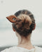 Premium teak wood hair clip with a glossy natural finish, catching sunlight to highlight its water-resistant durability.