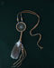 Tiny handcrafted dream catcher pendant on a leather cord, resting on a bed of dried lavender and crystals