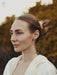 Close-up of the hairpin's warm wood tones and subtle grain, pinned into a half-up hairstyle for understated elegance.