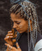 Woman with braided hair holding a wooden object against a dark background