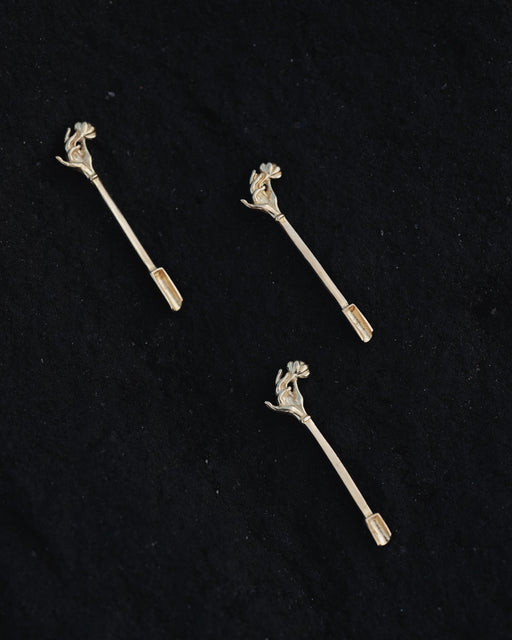 Three silver floral hair pins on a black background