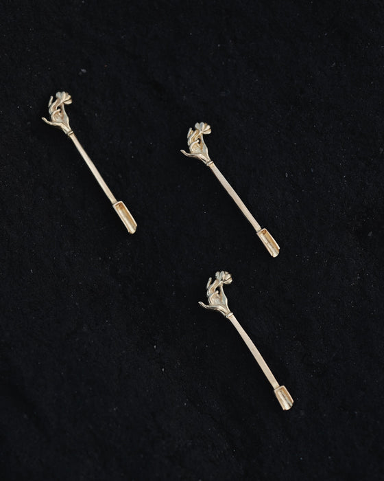Three silver floral hair pins on a black background