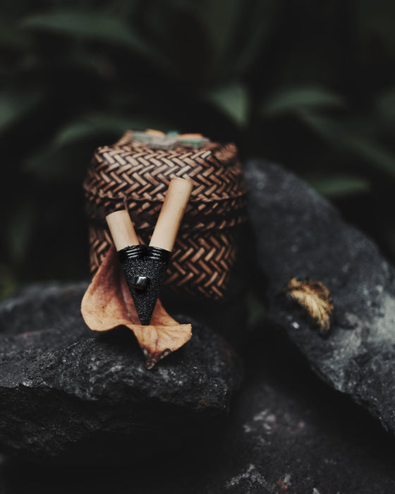 Hand-carved bamboo snuff pipe coated in volcanic ash, featuring polished hematite stones for energy grounding during hapé rituals
