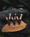 Five black and beige earrings on a brown leaf with a dark background