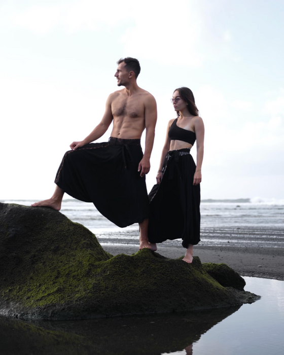 Two people in black outfits standing on a rock by the water, with 'Ayaho' logo in the corner.