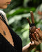 Person holding a traditional wooden tool with beads against a blurred natural background