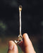 Held aloft, a premium metal Spiritual Powder Spoon intricately crafted for precise use in shamanic rituals and as a decorative element for kuripe pipes