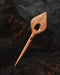 Hand-polished wooden clip with a tapered leaf silhouette, displayed on woven rattan to emphasize its eco-friendly appeal