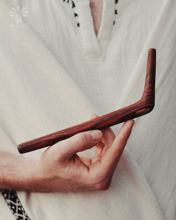 Hand holding a wooden tool against a white background