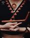 Person wearing a patterned top and holding a wooden object with Ayaro logo.