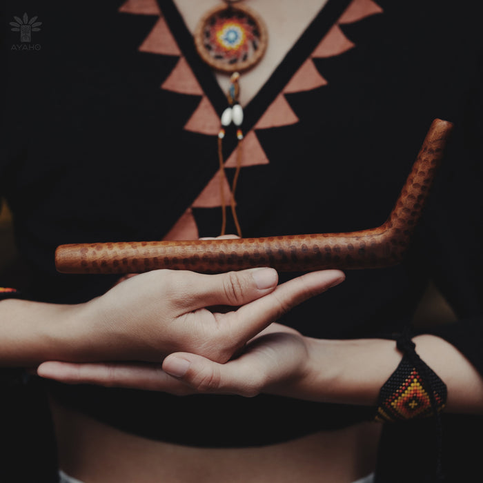 Person holding a wooden tool with a patterned background