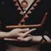 Person holding a wooden tool with a patterned background