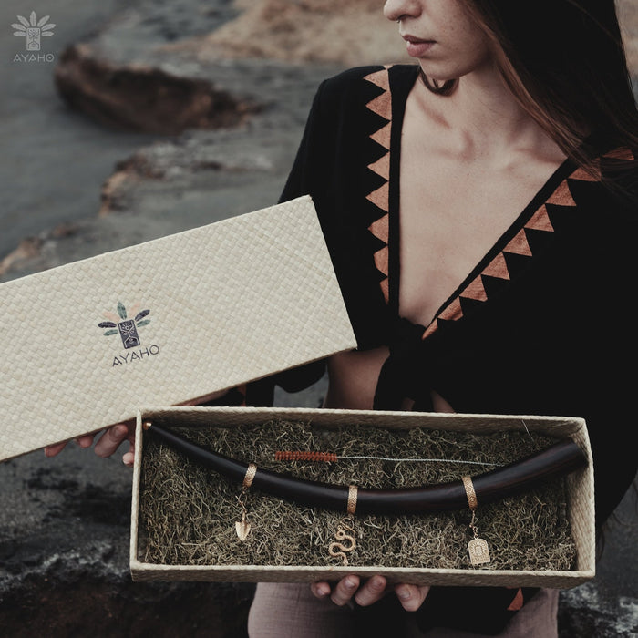 A person holding a box containing a shamanic Tepi, which is a smoking accessory made of mango wood and rosewood with silver and bronze tips, and embellishments.