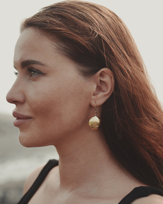 Circular bronze hoops with dangling mirror charms, styled with a linen dress for boho festival vibes