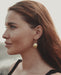 Circular bronze hoops with dangling mirror charms, styled with a linen dress for boho festival vibes