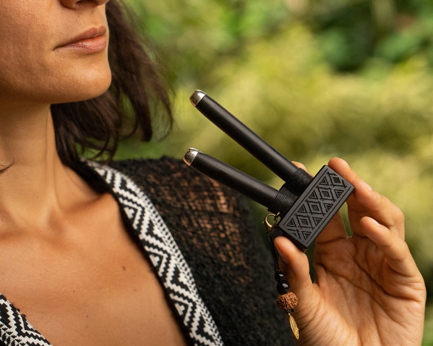 Woman holding a black hair straightener against a blurred green background