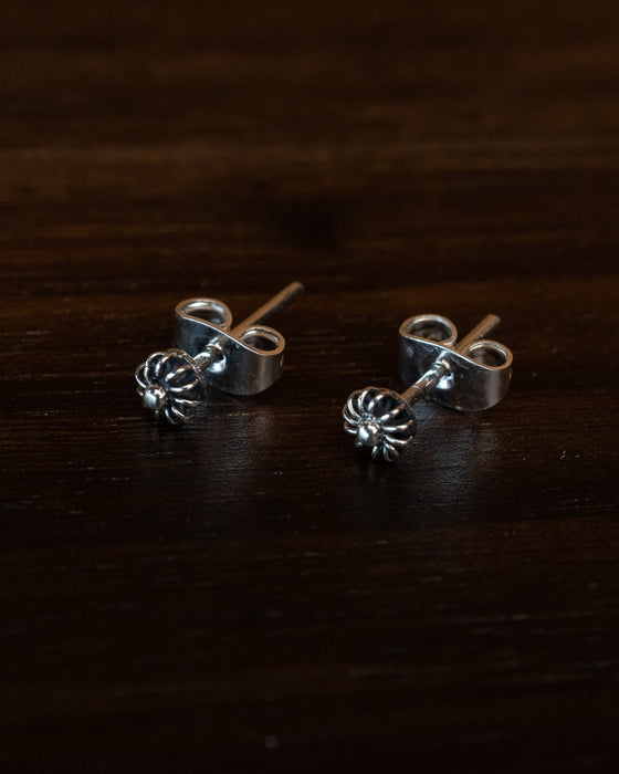 Close-up of hand-engraved floral stud earrings with cubic zirconia centers, displayed on a rustic wooden tray with dried lavender for boho charm.