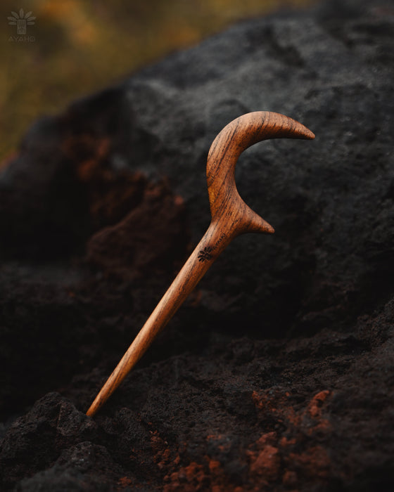 Teak wood crescent hair accessory on a beach towel, highlighting its water-resistant natural finish