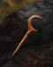Teak wood crescent hair accessory on a beach towel, highlighting its water-resistant natural finish