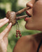 Sacred Ayahuasca vine kuripe pipe adorned with rudraksha and goldstone, a handcrafted symbol for hape snuff rituals, nestled in natural greenery.