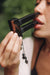 Person using a lip gloss applicator with a blurred green background