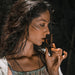 Woman holding a wooden object close to her face against a dark background