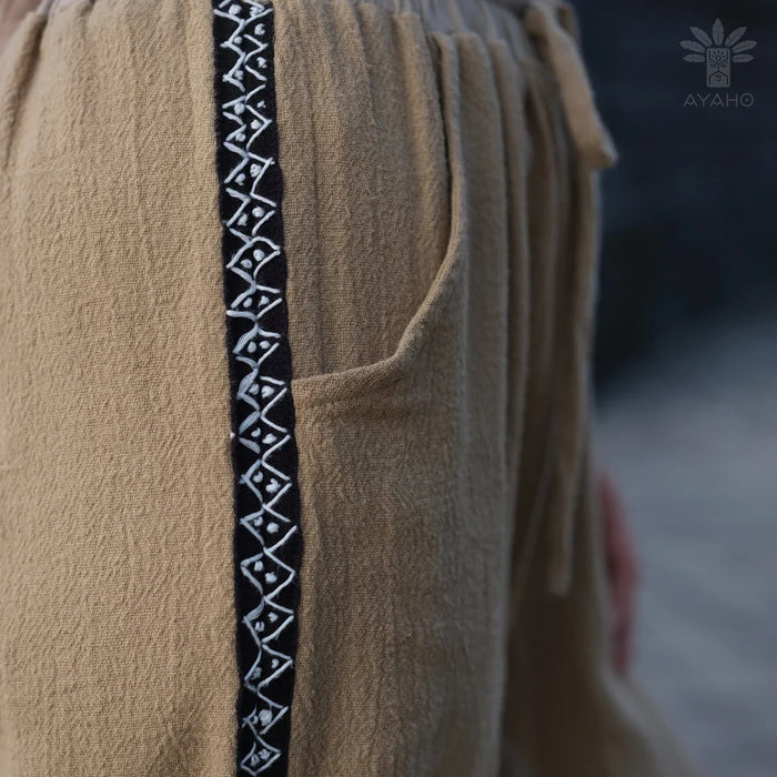 Close-up of a beige garment with a black and white patterned trim, featuring the AYANO brand logo.