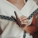 Person holding a wooden hair clip with intricate design, wearing a white top.