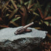 Wooden eagle head pipe on a rock with plants in the background
