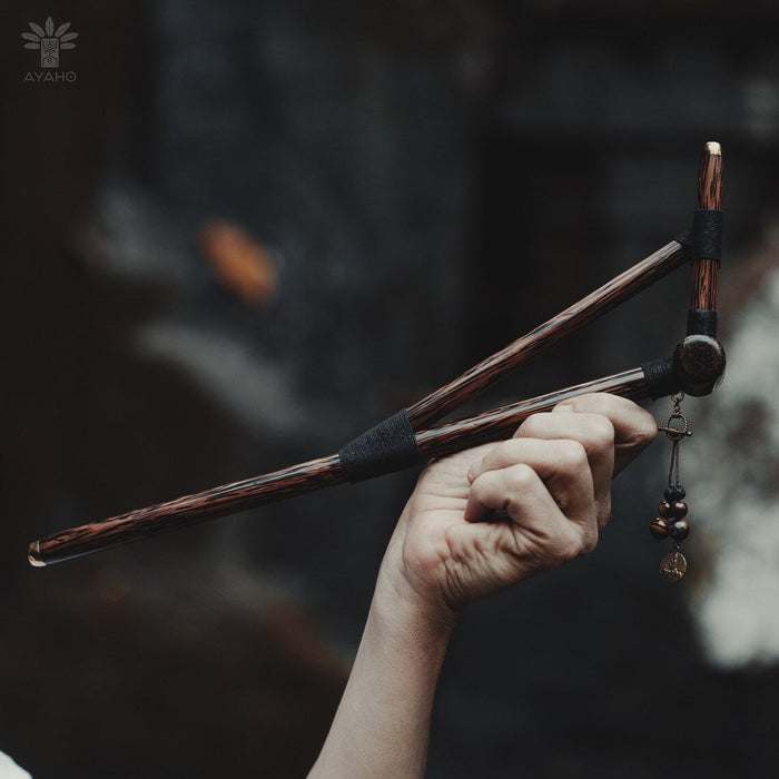 Hand holding a pair of wooden drumsticks with a blurred background