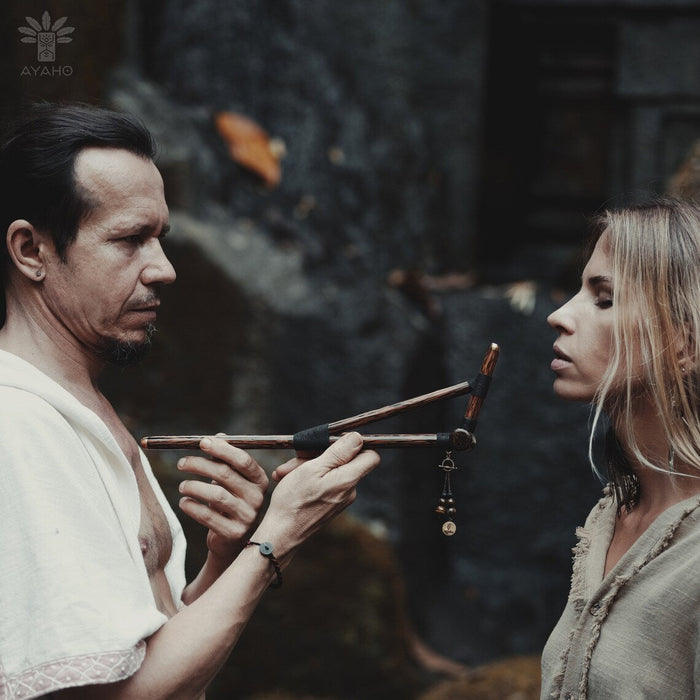 Man holding a bow and arrow towards a woman in a forest setting