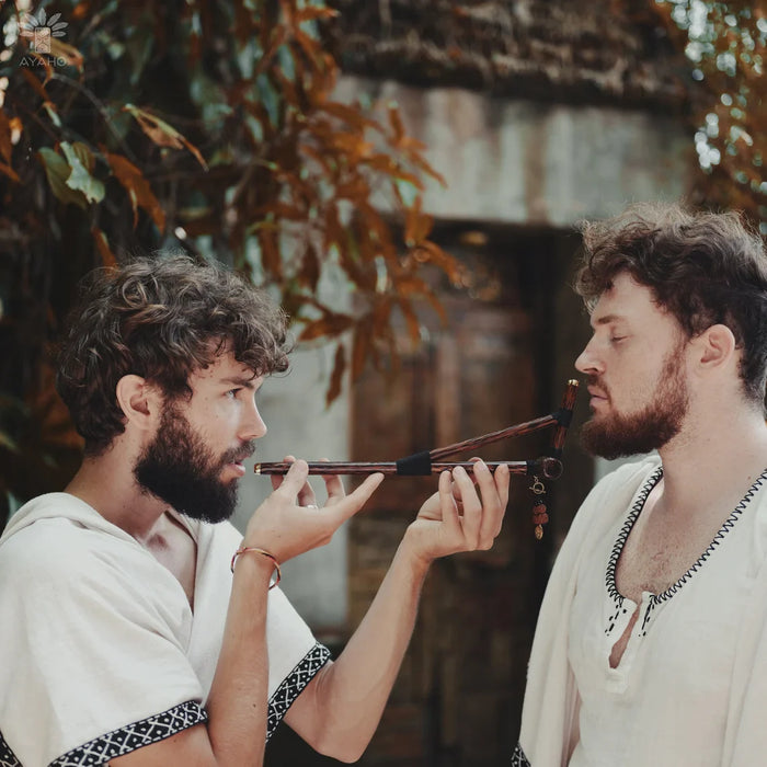 Two men in historical attire playing a flute outdoors.