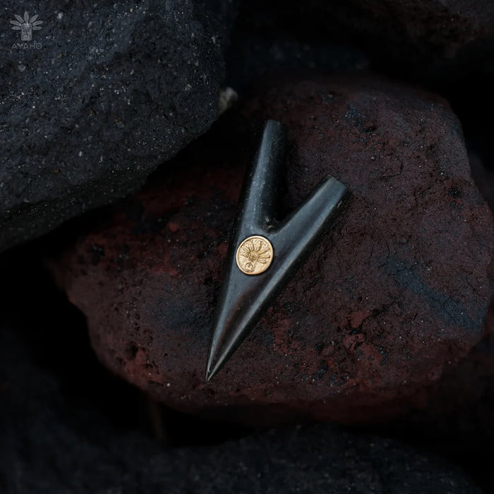 Black arrowhead with a gold center on a dark stone surface
