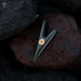 Black arrowhead with a gold center on a dark stone surface